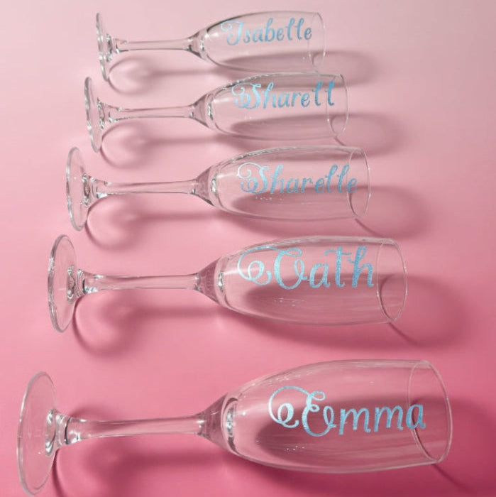 Set of personalized champagne flutes with names on a pink background